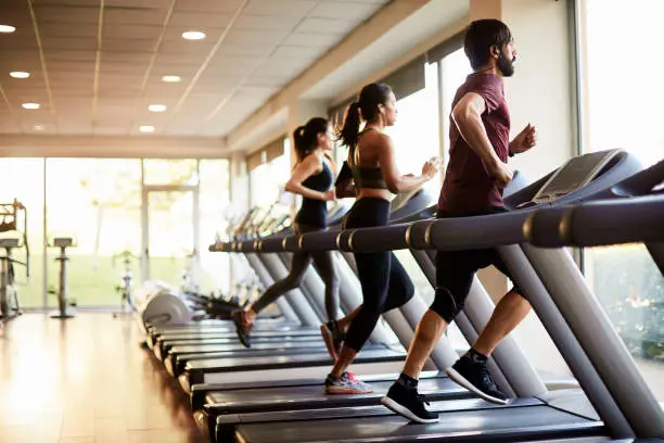 People running on treadmills in a gym, pushing through post-leg day soreness.