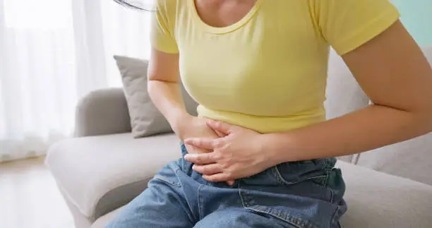 Close-up of a woman experiencing abdominal discomfort, often linked to weight gain during ovulation.