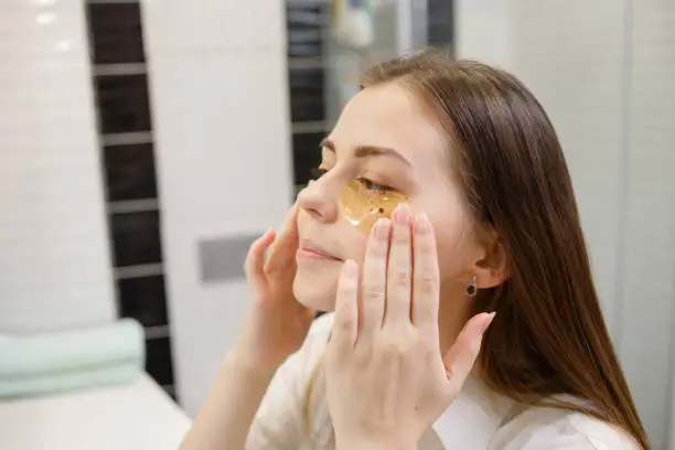 A woman applying honey under her eyes as a natural skincare treatment, highlighting the moisturizing and antibacterial benefits of honeycomb.