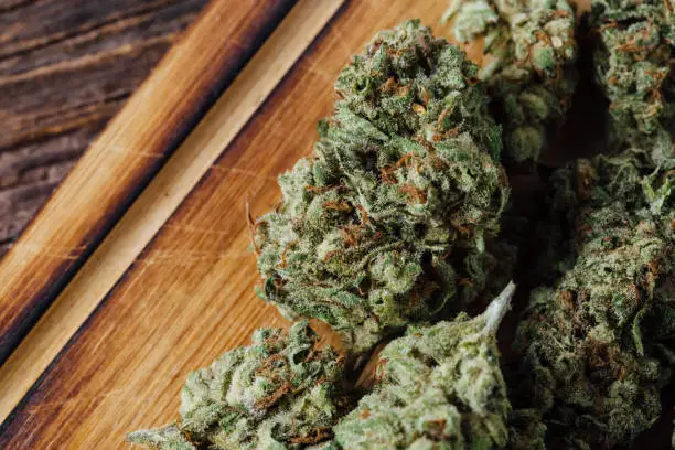 A close-up of cannabis buds on a wooden surface, raising the question: Does weed have calories?