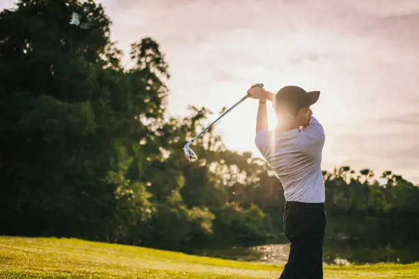 Golfer executing a strong swing on the course at sunset, highlighting the benefits of golf strength training for power and endurance.